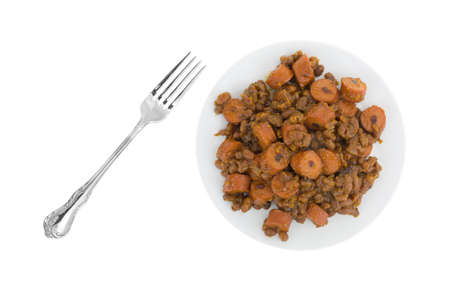 Top view of baked beans and sliced hot dogs on a plate with a fork to the side isolated on a white background.の写真素材