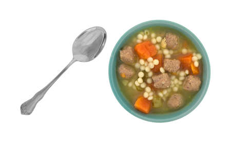 Top view of a bowl filled with Italian style wedding soup with a spoon to the side isolated on a white background.の写真素材