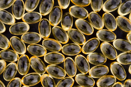 Top view of a group of vitamin a gel capsules on a black background.