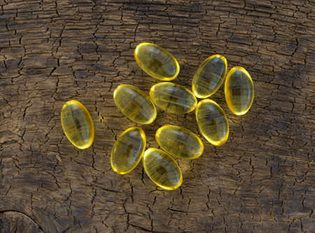 Top view of a group of vitamin a gel capsules on an old brown wood board.の写真素材