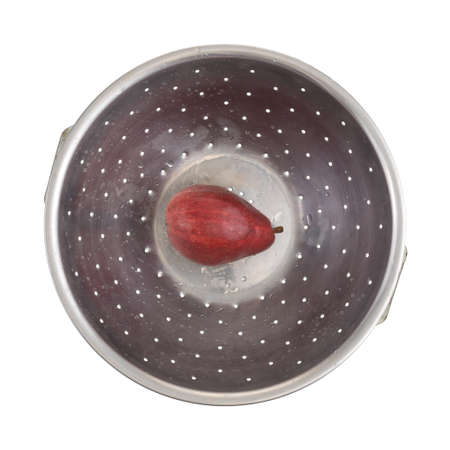 Top view of a single red pear that has been rinsed at the bottom of an old stainless steel colander isolated on a white background.の写真素材