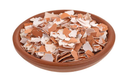 Small bowl filled with crushed egg shells isolated on a white background.