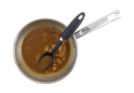 Top view of leftover steak and potatoes stew in a steel skillet with a black spoon in the food isolated on a white background.の写真素材