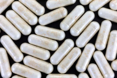 Top view of a group of nicotinamide riboside capsules on a black background.の写真素材