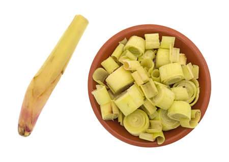 Top view of a small red clay bowl filled with cut lemon grass plus a small stalk isolated on a white background.の写真素材