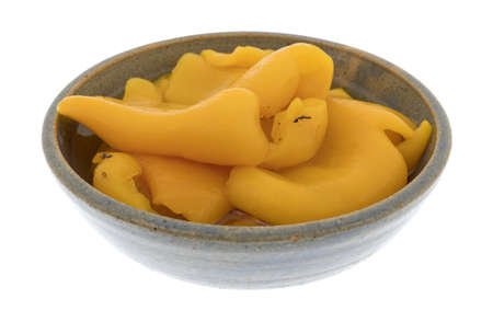 Side view of a serving of roasted yellow peppers in a stoneware bowl isolated on a white background.の写真素材