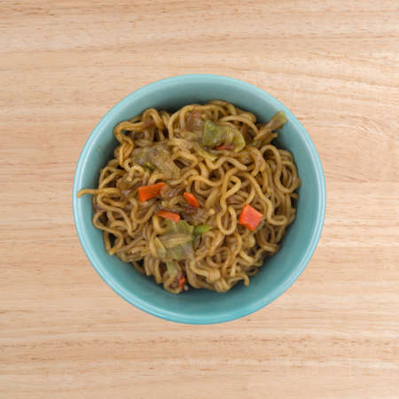 Top view of a serving of beef flavored ramen noodles in a bowl on a wood table.の写真素材