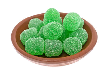 A small bowl filled with green sugar coated sour drop candy isolated on a white background.の写真素材