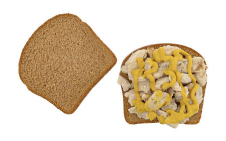 Top view of spicy chicken breast on a slice of wheat bread with mustard and another piece to the side isolated on a white background.の写真素材