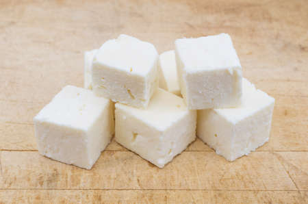 Several chunks of feta cheese on an old wood cutting board.の写真素材