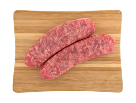 Top view of two mild bratwurst sausages on a wood cutting board isolated on a white background.の写真素材