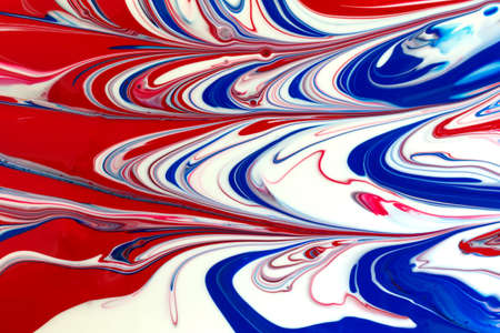 A close view of wet colorful red white and blue poster paint brushed into an abstract design.の写真素材