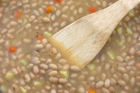 Hot bean and carrot soup with a wood spoon in the food.の写真素材