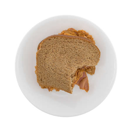 Top view of a bitten red curry flavored tuna fish sandwich on a small plate isolated on white...