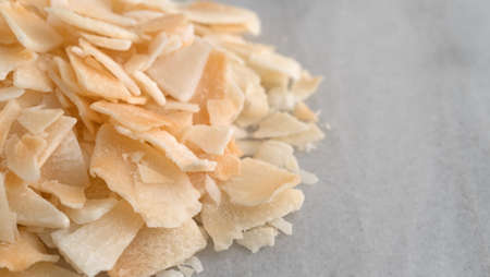 Side close view of toasted coconut flakes on a gray marble cutting board.の写真素材