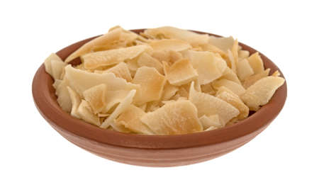 A small terracotta bowl filled with coconut flakes isolated on a white background.の写真素材