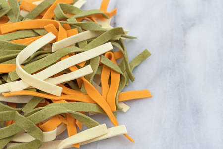 Side view of a portion of colorful vegetable noodles on a gray marble cutting board.の写真素材