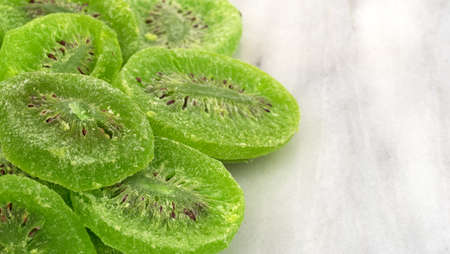 Several slices of glazed kiwi fruit on a gray marble cutting board.の写真素材