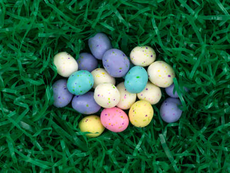 Top view of a group of speckled Easter egg malt ball candies nestled in a green plastic grass.