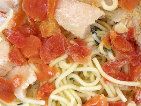 Close view of a frozen TV dinner of sliced chicken breast with angel hair pasta in a tomato sauce.の写真素材
