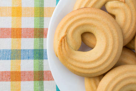 Top close view of a white plate with shortbread cookies on a colorful cloth place mat.
