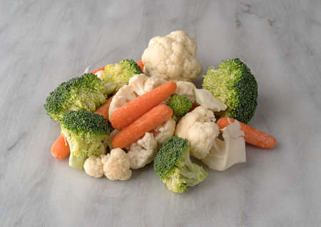 Raw carrots, broccoli and cauliflower on a gray marble counter top.の写真素材