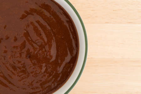 Top close view of a small bowl filled with pulled pork starter sauce on a wood table.