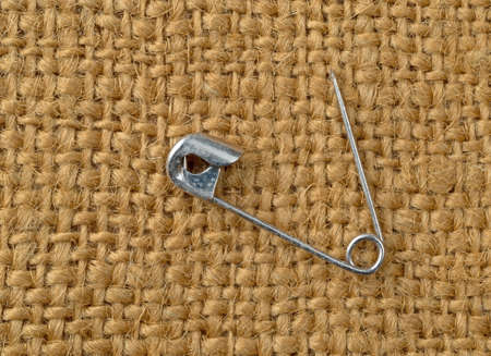 Top view of an old steel safety pin on a piece of burlap cloth.の写真素材