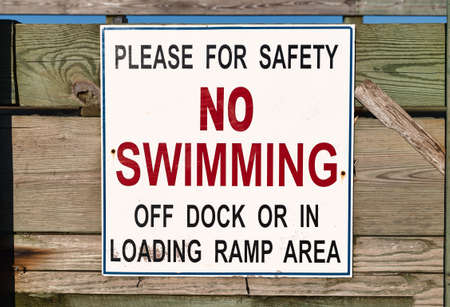 Close view of a no swimming sign on a public pier.の写真素材