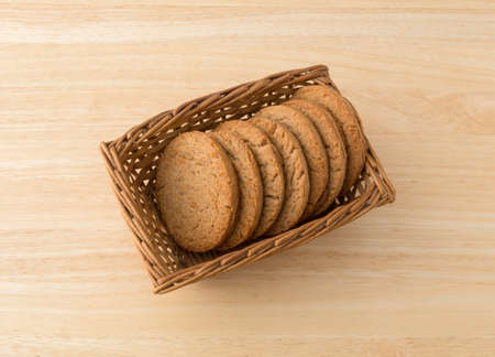 A basket with several brown sugar and cinnamon cookies on a wood table.