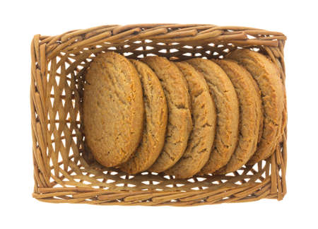 A small wicker basket with several brown sugar and cinnamon cookies isolated on a white background.の写真素材
