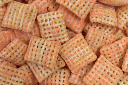 Close view of small cheddar cheese flavored crispy rice crackers isolated on a white background.