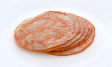 Side view of several slices of buffalo style chicken breast luncheon meat on a plate.の写真素材