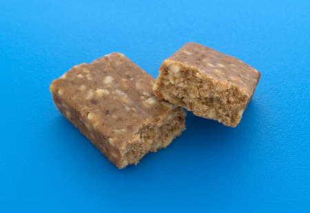 A broken in half cashew and date energy bar on a bright blue cutting board.の写真素材