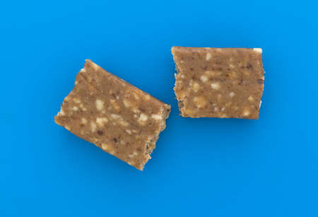 Top view of a broken in half cashew and date energy bar on a bright blue cutting board.の写真素材