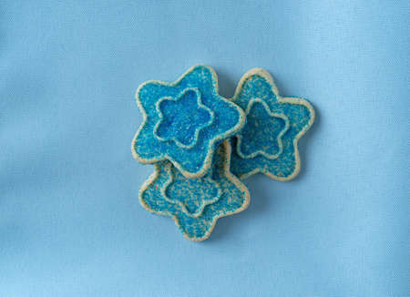 Top view of three star shaped sugar cookies with blue sprinkles on a cloth napkin.の写真素材