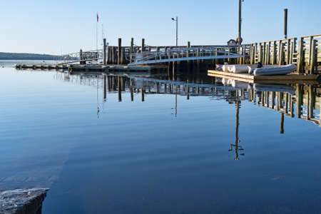 Public pier plus boats and dinghies on a floating dock on Penobscot Bay at Searsport, Maine in the early morning light.の写真素材