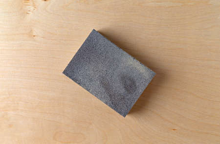 Top close view of a sanding sponge atop a piece of birch plywood.