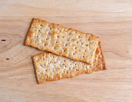 Top view of two multigrain flatbread crackers on a wood cutting board.の写真素材