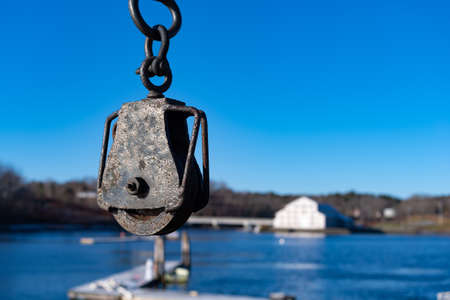Close view of an old pulley used for hauling lobster traps and fish catches off boats with water and...
