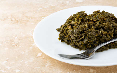 Side view of a portion of chopped kale on a white plate atop a marble table.の写真素材