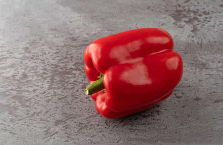 Side view of a whole red bell pepper on a gray counter top.の写真素材