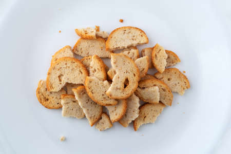 Overhead view of broken pieces of sesame round melba toast on a white plate.の写真素材