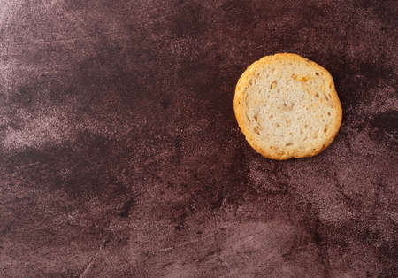 Overhead view of a single sesame round melba toast offset on a maroon background.の写真素材
