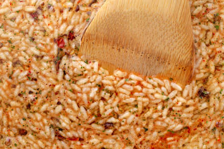 Side view of Mexican rice and beans mix in a skillet cooking with a wood spoon in the food...