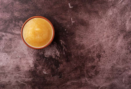 Overhead view of a small bowl filled with sugar free applesauce offset on a maroon background.の写真素材