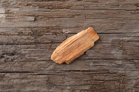 A single alder wood smoking chip for barbecuing on a weathered background.