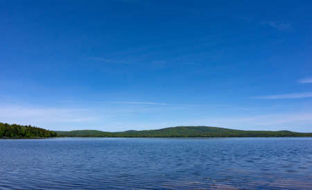 Wide view of Branch Lake with blue sky above and wispy clouds on a summer day in Maine.の写真素材