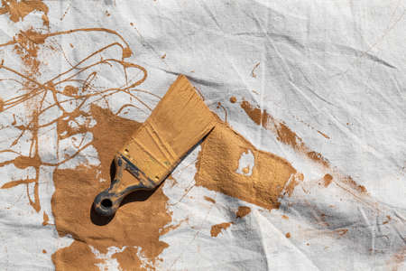 Painters drop cloth with brown paint covering a used brush.の写真素材