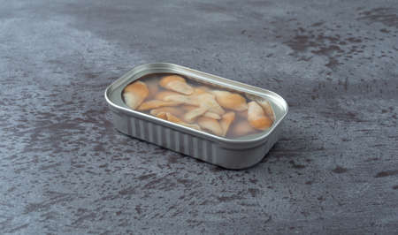 Side view of an open tin of razor clams in water on a gray table illuminated with natural lighting.の写真素材
